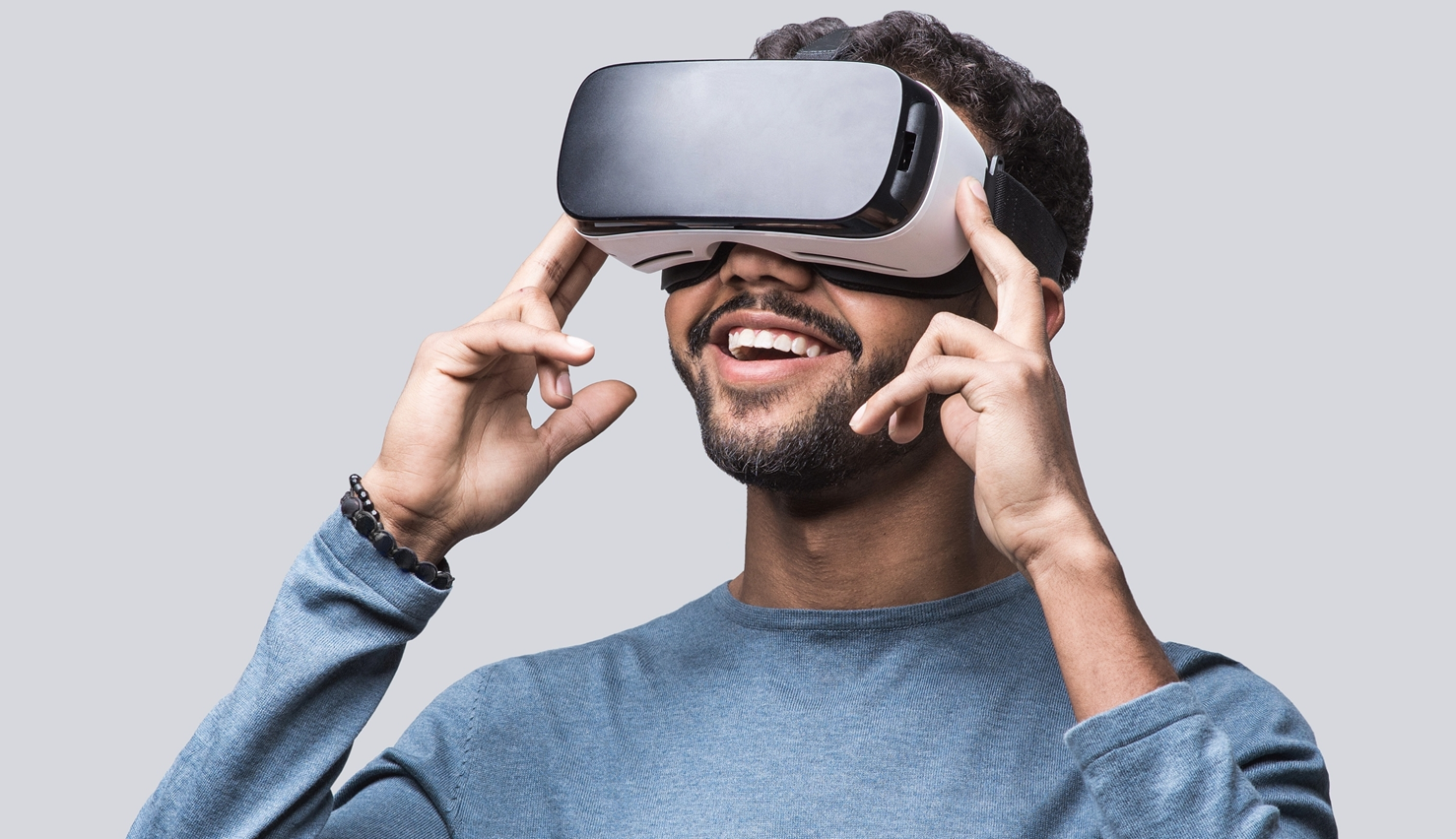 A young man smiling, while he is wearing virtual reality glasses